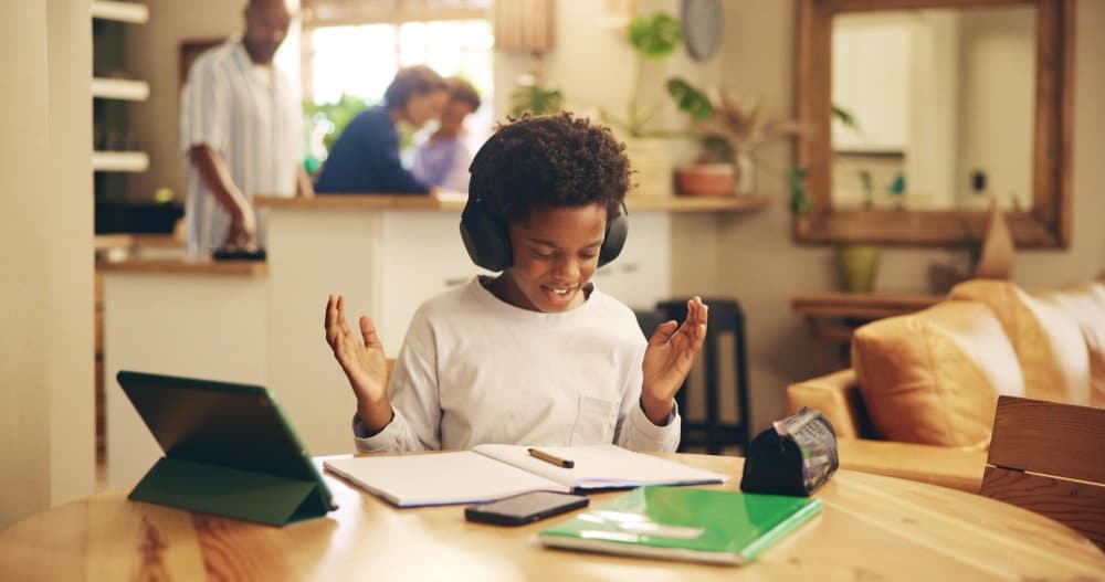 An excited child with headphones celebrating his education and studying for exam while using secure cloud services.