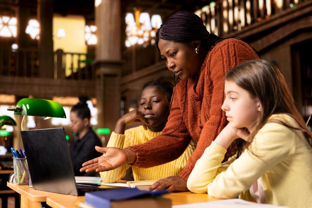 A female teacher assisting students with class homework and mentoring them.